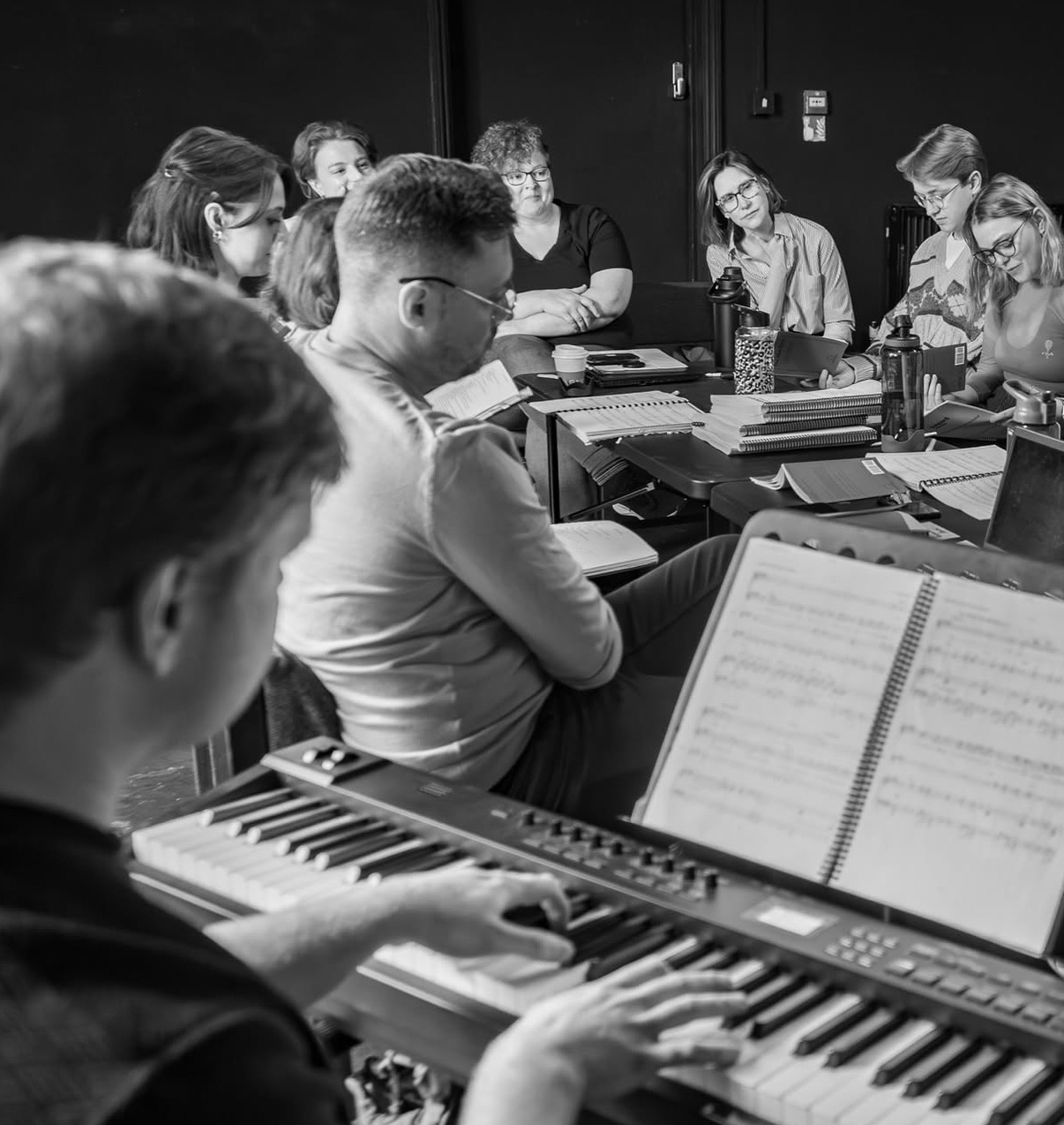 A creative team gathered around a sunlit worktable in a Yorkshire rehearsal room